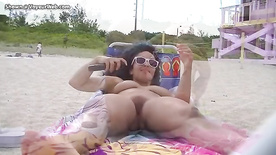 Nua na praia pegando sol sendo filmada por voyeur